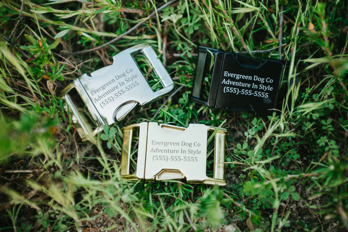 Three metal Quick Release Buckles with engraved text on grass