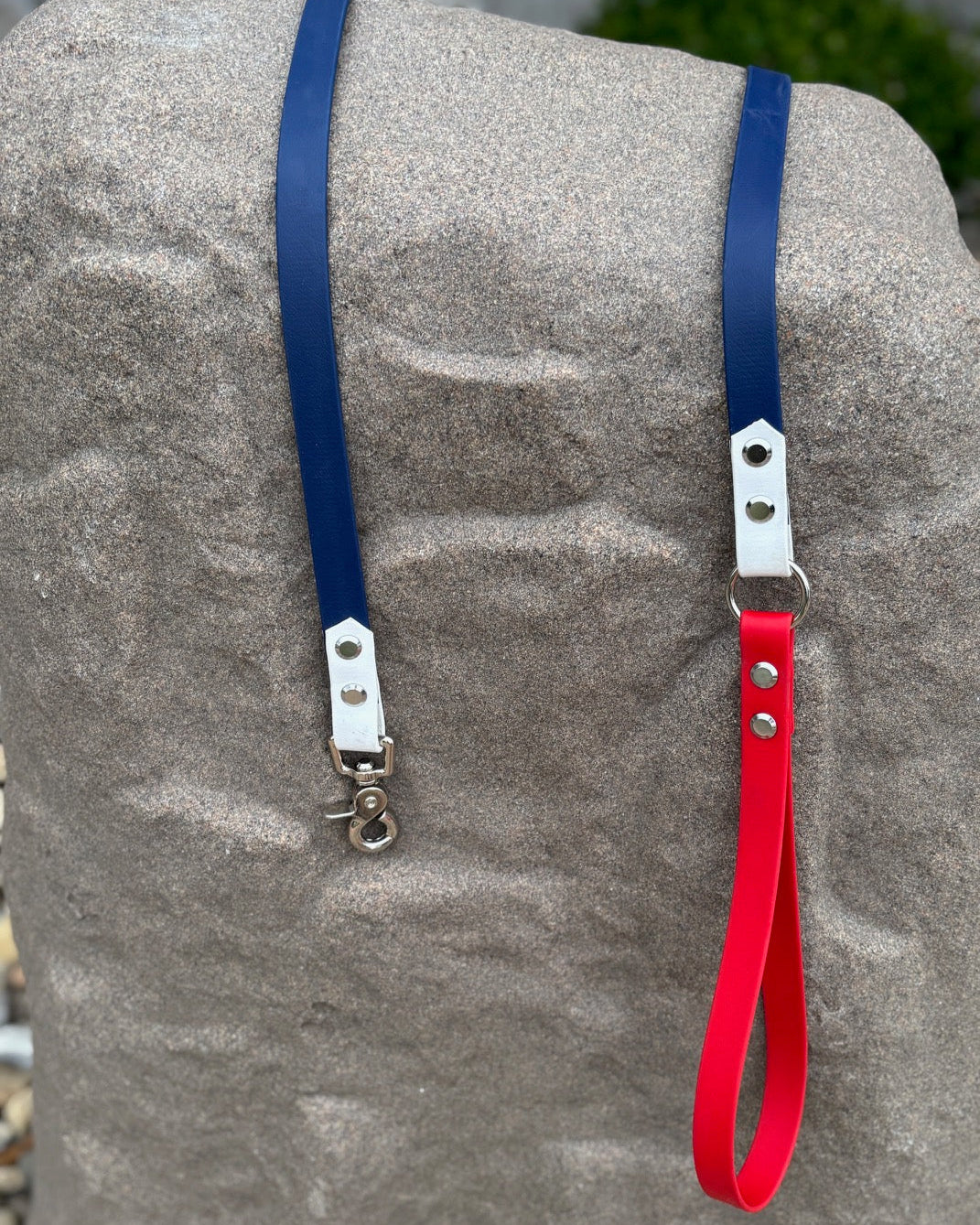 Patriotic Pup classic dog leash resting on a rock. The leash has an open-loop handle and is made from Navy Blue, Arctic White and True Red BioThane.