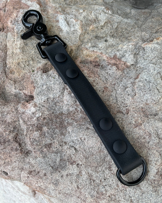 A StraightLine GearSnap made from Evergreen Dog Co placed on a rock. The material is Midnight Black color with a black trigger snap and black O-Ring