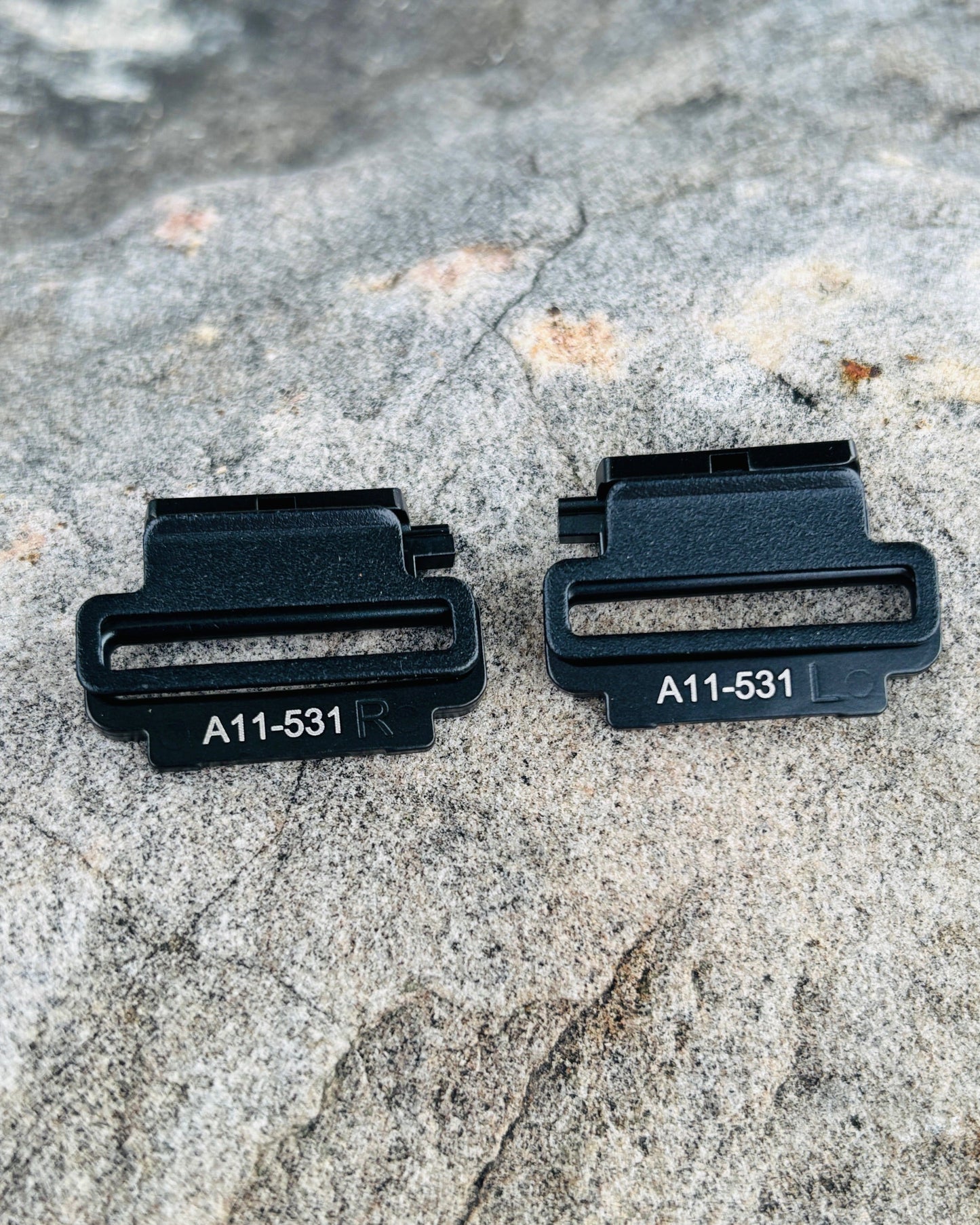 A set of Fi Endlinks resting on a rock with a white serial number inscribed on the bottom of them.
